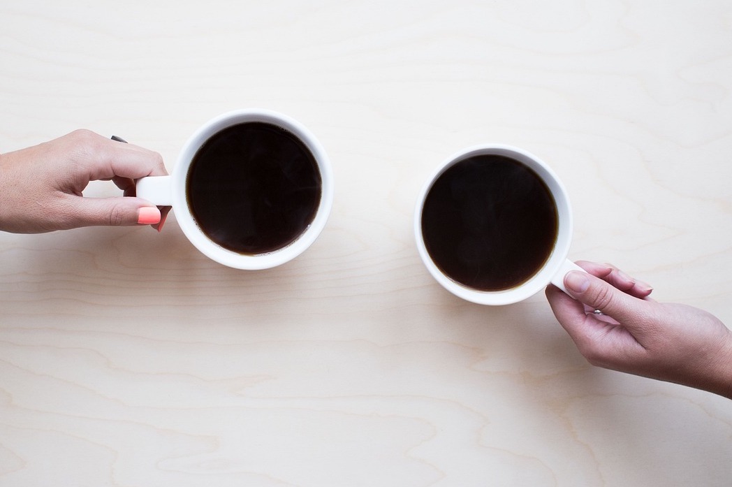 two hands holding coffee mugs