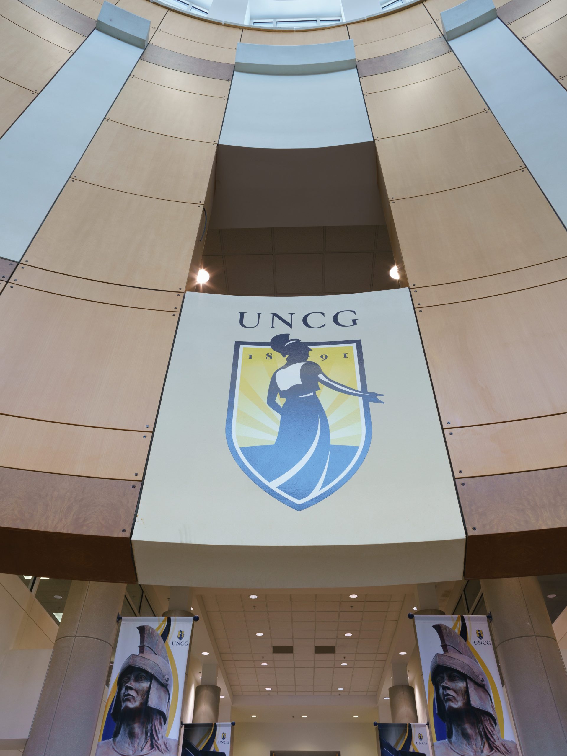 EUC Atrium with Minerva UNCG Logo center, flanked by two UNCG Athletic Spartan Statue image banners